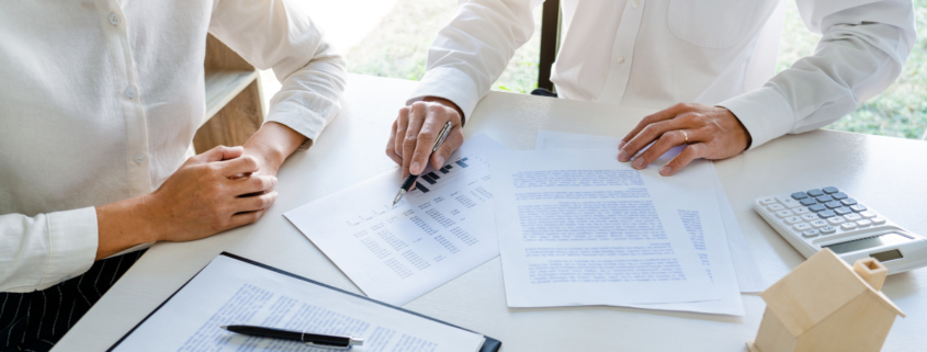 two Healthcare Insurance Brokers discussing margins and looking over paperwork in an office