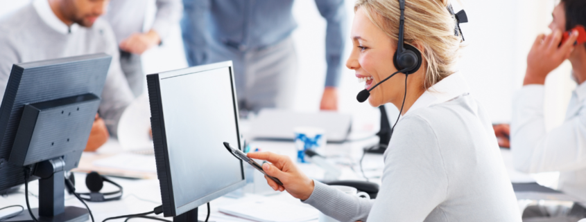 blonde customer service representative sitting at a desk on a computer providing support